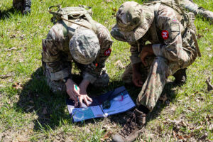 Soldiers studying a map outdoors.