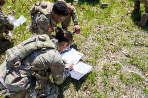 Soldiers studying documents outdoors.